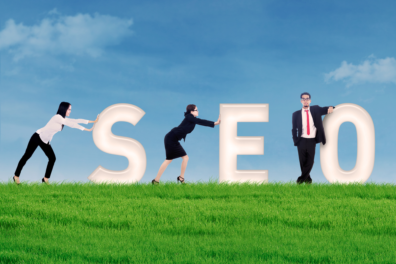 Business people pushing SEO letter on grass under blue sky